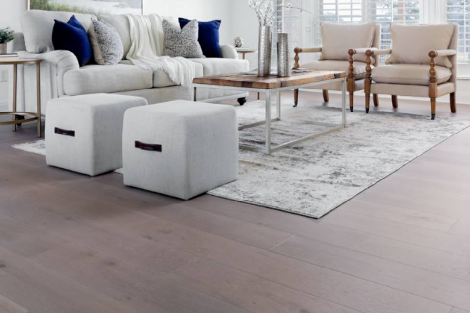 brown hardwood flooring in living room with area rug and couch and chairs.